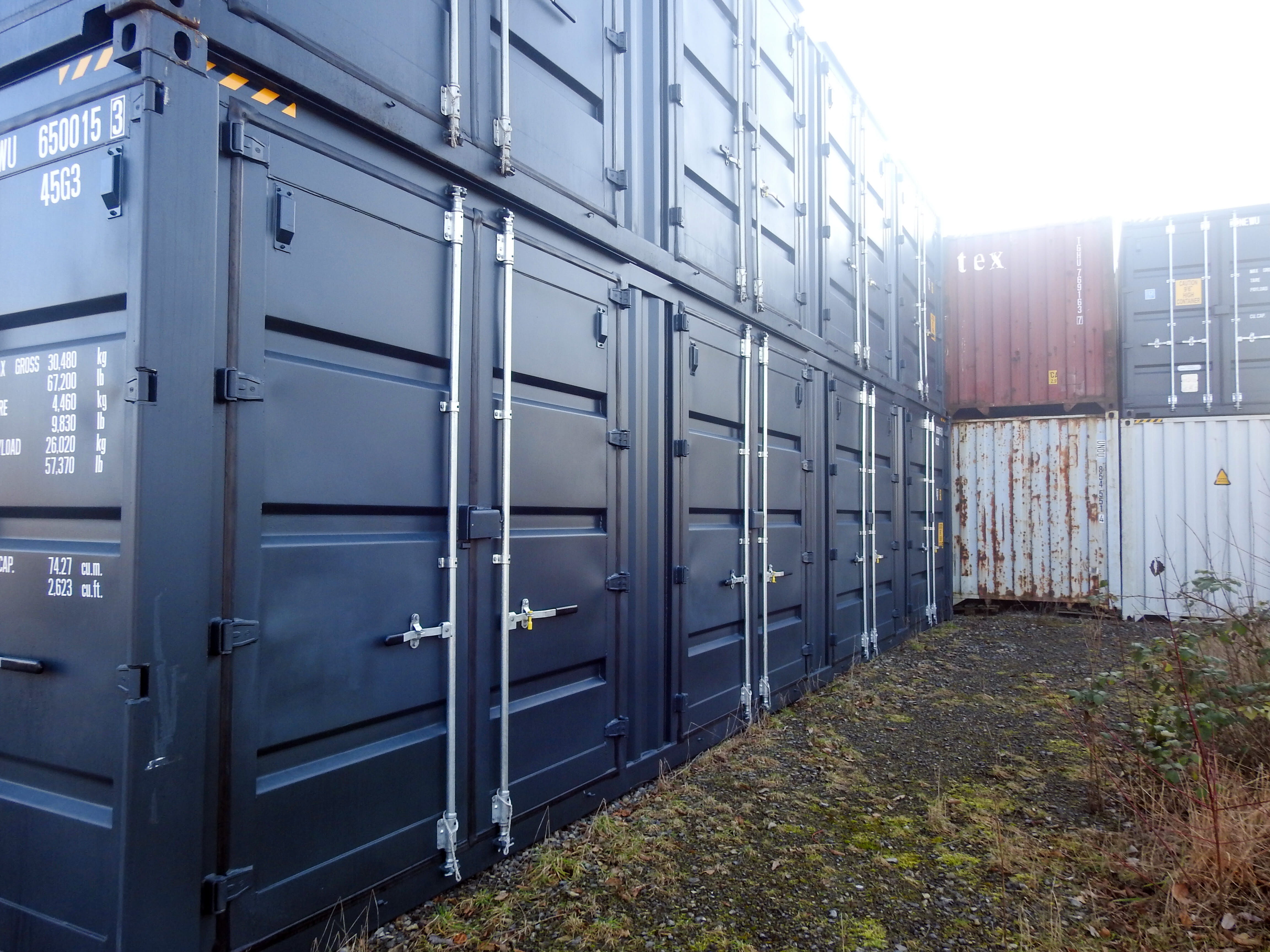 Mehrere dunkelblaue Container sind auf einem Außengelände ordentlich übereinander gestapelt – BOBE